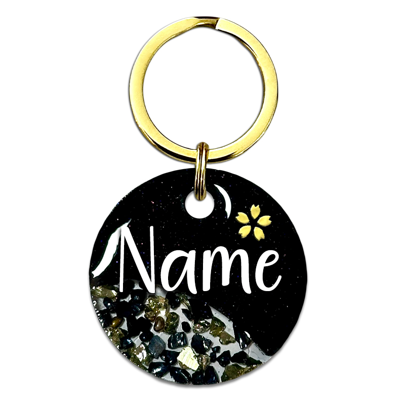 A picture of Ein funkelnder schwarzer Traum mit goldenen Highlights! Diese Marke kommt in einem raffinierten Split-Design mit schwarzem Perlpigment und einem klaren Bereich gefüllt mit funkelnden Glassteinen. Abgerundet wird das Design mit einer kleinen Kirschblüte oberhalb des Tiernamens sowie goldenen Glitzersteinen.