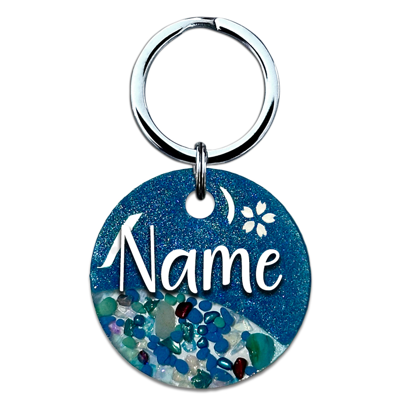 A picture of Ein funkelnder blauer Traum mit goldenen Highlights! Diese Marke kommt in einem raffinierten Split-Design mit blauem Perlpigment und einem klaren Bereich gefüllt mit funkelnden Glassteinen. Abgerundet wird das Design mit einer kleinen Kirschblüte oberhalb des Tiernamens sowie goldenen Glitzersteinen.