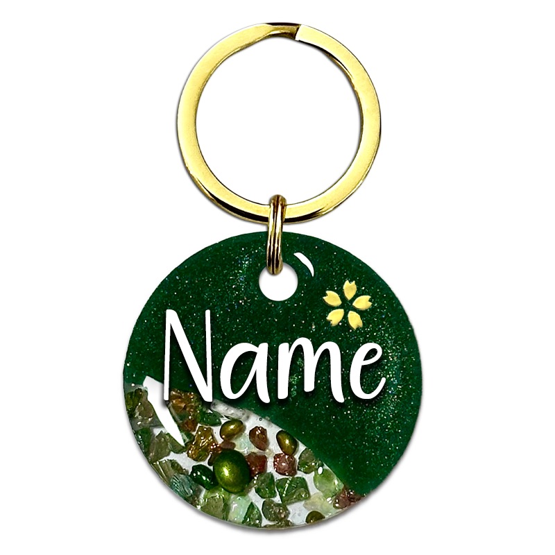 A picture of Ein funkelnder grüner Traum mit goldenen Highlights! Diese Marke kommt in einem raffinierten Split-Design mit grünem Perlpigment und einem klaren Bereich gefüllt mit funkelnden Glassteinen. Abgerundet wird das Design mit einer kleinen Kirschblüte oberhalb des Tiernamens sowie goldenen Glitzersteinen.