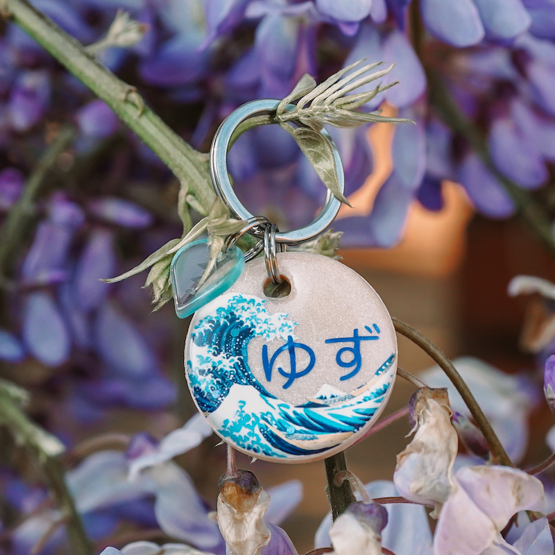 A picture of 28 mm im Durchmesser – die erste Marke aus dem Ukiyo-e Special ehrt Katsushika Hokusais berühmte „Große Welle vor Kanagawa“ (ca. 1830). Die Welle erhebt sich vor einem beigen Hintergrund aus schimmerndem Perlpigment – feine Glitzer-Highlights runden das Design ab. Die Marke kommt inklusive blauer Metallic-Beschriftung* und passendem blauen Blatt-Charm.
