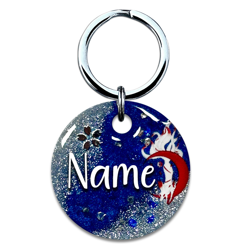 A picture of Die japanische Mythologie ist bekannt für viele Geister und Gottheiten. Inari ist eine japanische Fuchsgottheit des Shintoismus. Vor nachtblauem Perlpigment mit weißen, glitzernden Akzenten umspielt der weiße Fuchs auf dieser Marke einen roten Sichelmond. Funkelnde Highlights aus goldenen und blauen Glitzersteinen runden das Design ab.