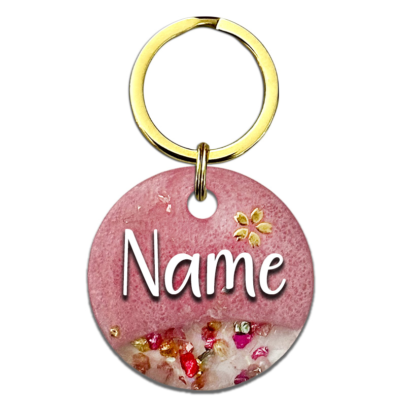 A picture of Ein funkelnder rosa Traum mit goldenen Highlights! Diese Marke kommt in einem raffinierten Split-Design mit rosenquarzfarbigem Perlpigment und einem klaren Bereich gefüllt mit funkelnden Glassteinen. Abgerundet wird das Design mit einer kleinen Kirschblüte oberhalb des Tiernamens sowie goldenen Glitzersteinen.